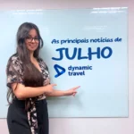 Mulher apontando para um quadro branco escrito: as principais atualizações do mês de julho do mercado de viagens corporativas.